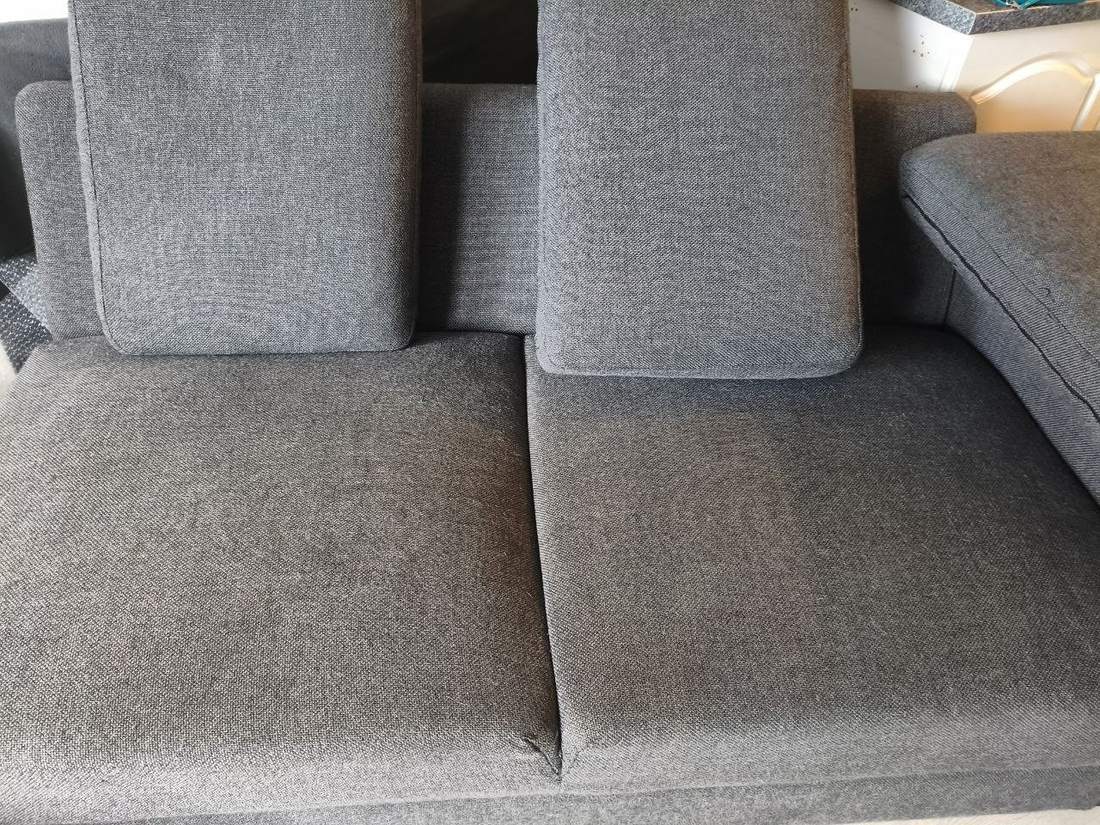 Graues Sofa mit Ottomane vor der Reinigung bei einem echten Einsatz